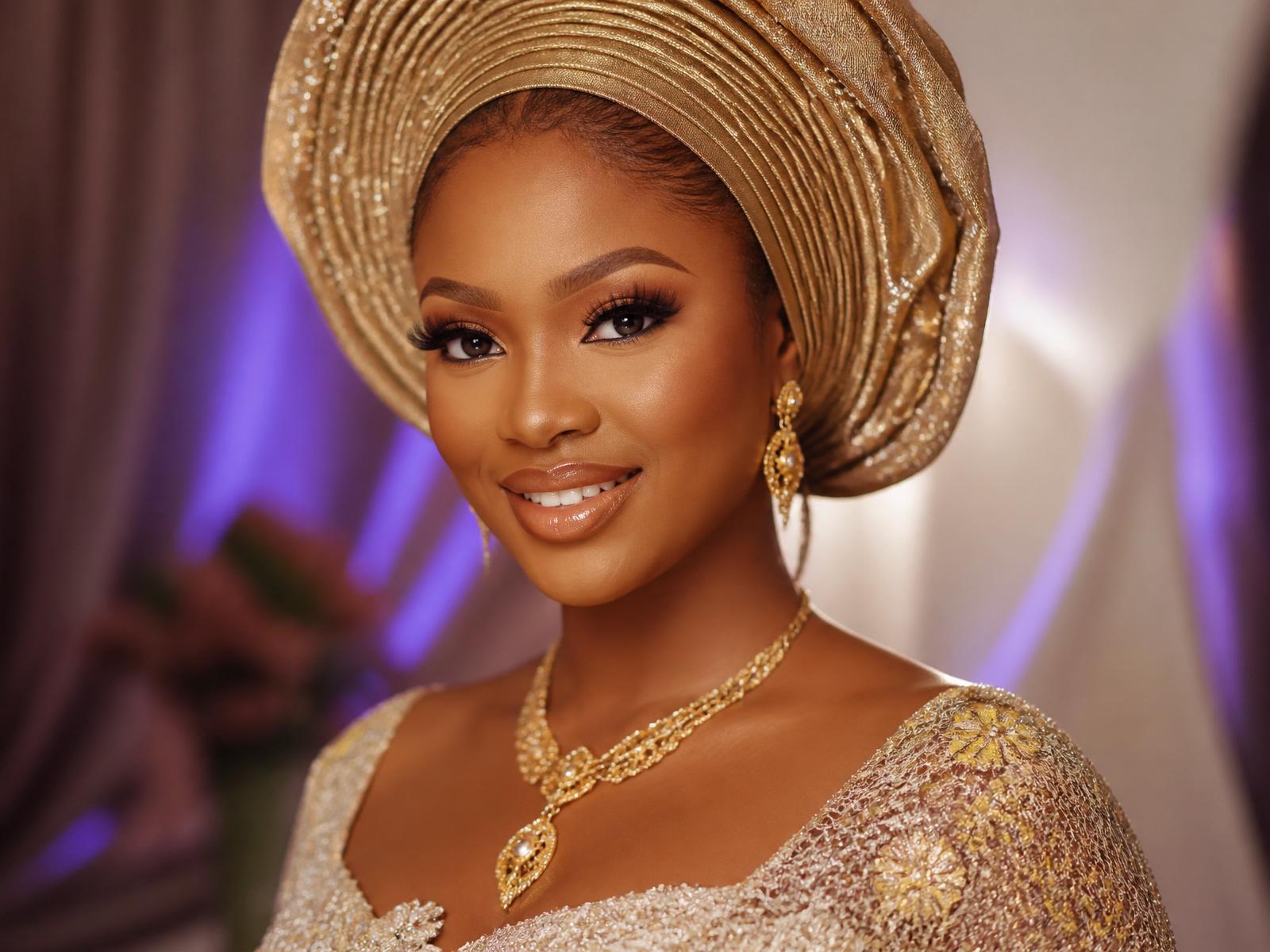 Nigerian bride with flawless glam bridal makeup and an elegant gold gele